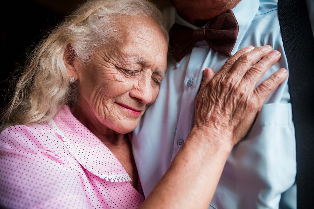 A happy elderly couple of a man and a woman, focused on the woman.