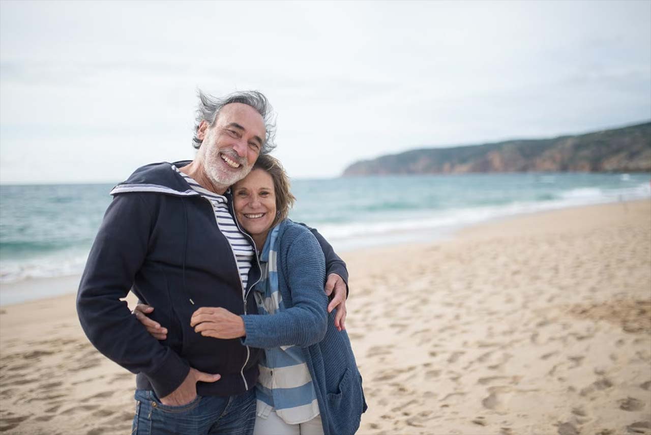 A happy elderly couple of a man and woman on a beach.